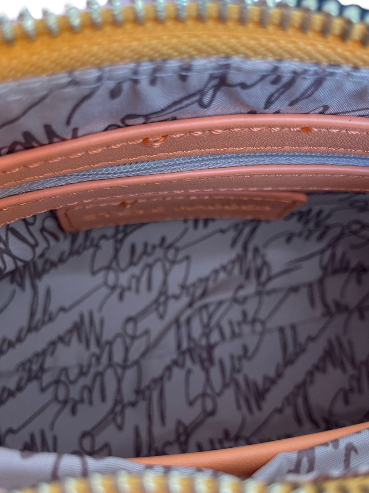 Interior de la bolsa Steve Madden naranja, mostrando compartimentos internos.