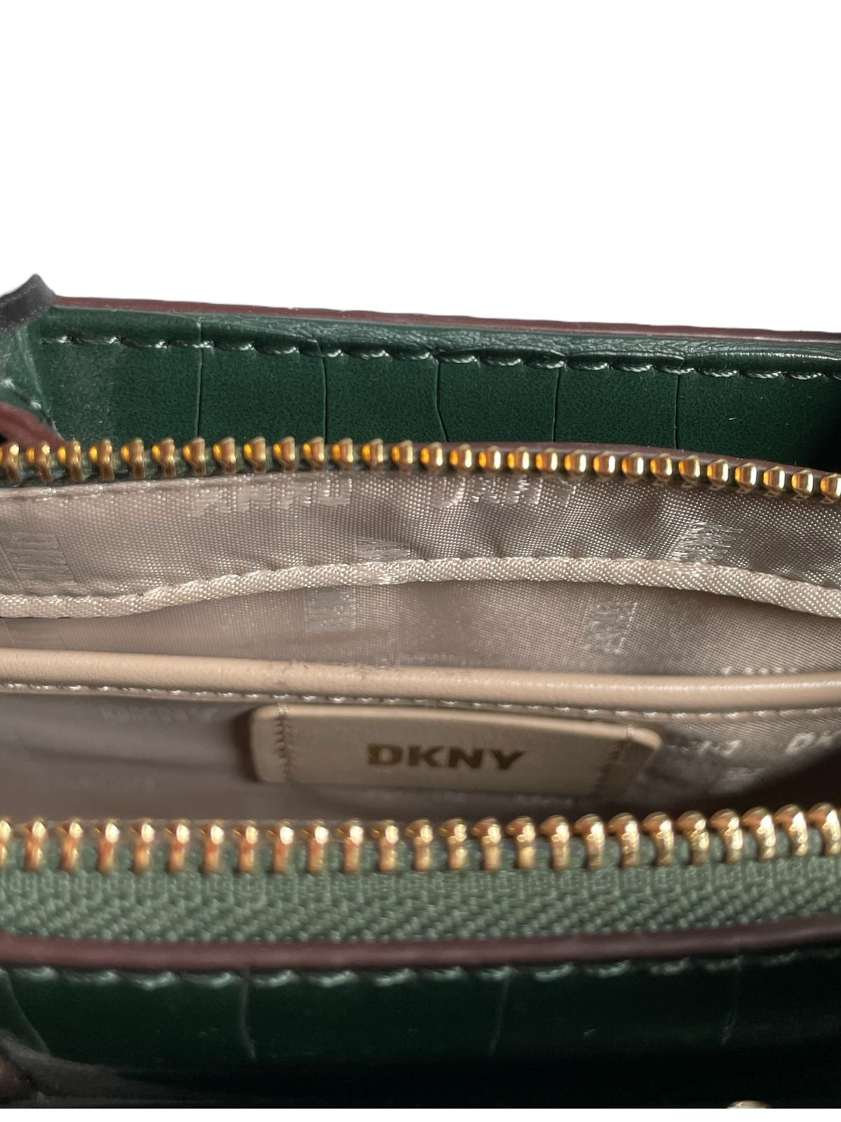 Interior de la bolsa de mano verde con correa DKNY, mostrando compartimentos internos