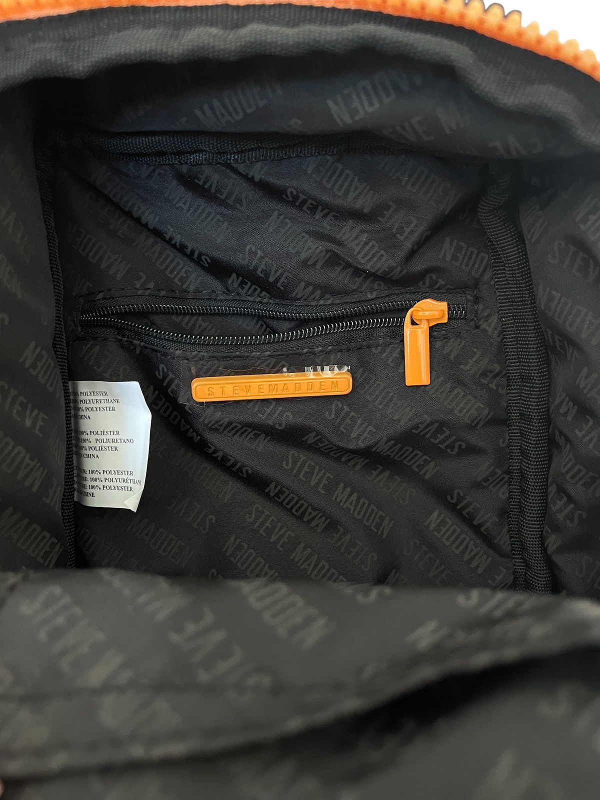 Interior de la bolsa Steve Madden naranja con termo, mostrando compartimentos internos y termo integrado.