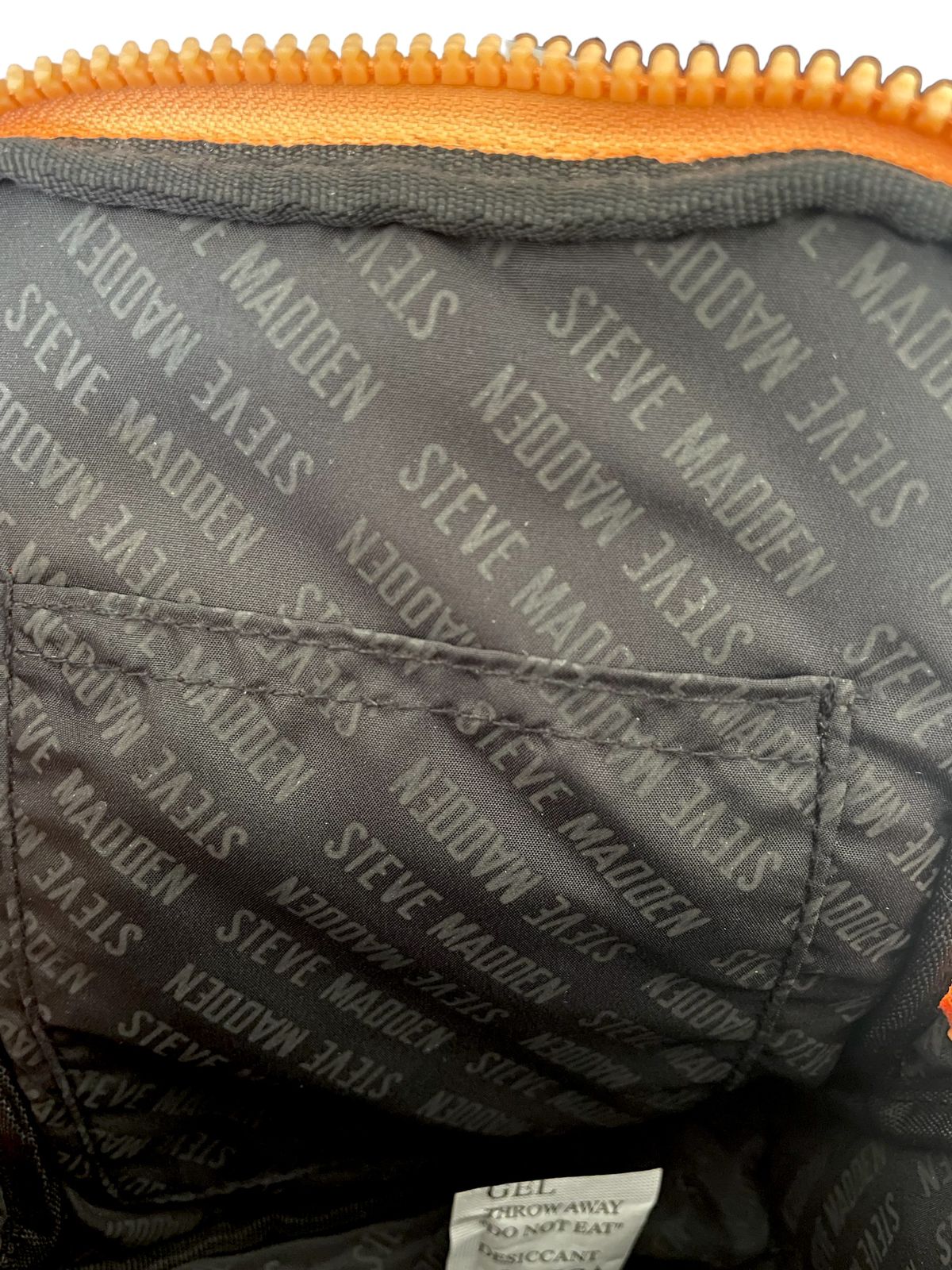 nterior de la bolsa Steve Madden naranja con termo, mostrando compartimentos internos y termo integrado.