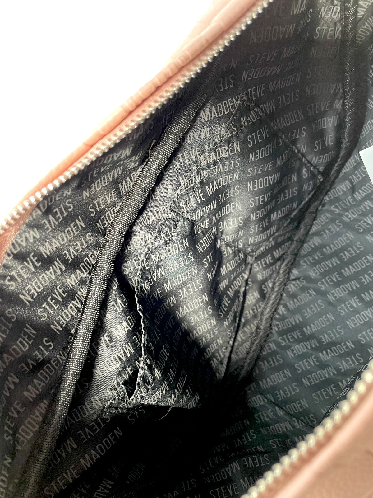 "Interior de la bolsa bandolera Steve Madden rosa, mostrando compartimentos internos."