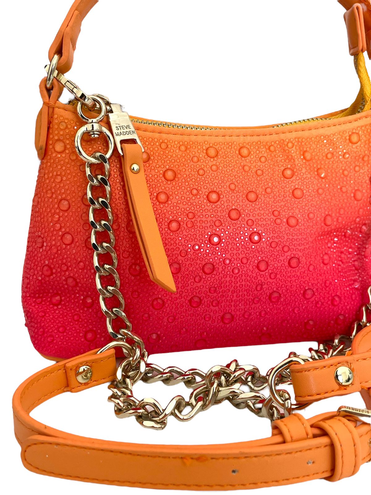 Detalles metálicos y correa ajustable de la bolsa Steve Madden naranja.